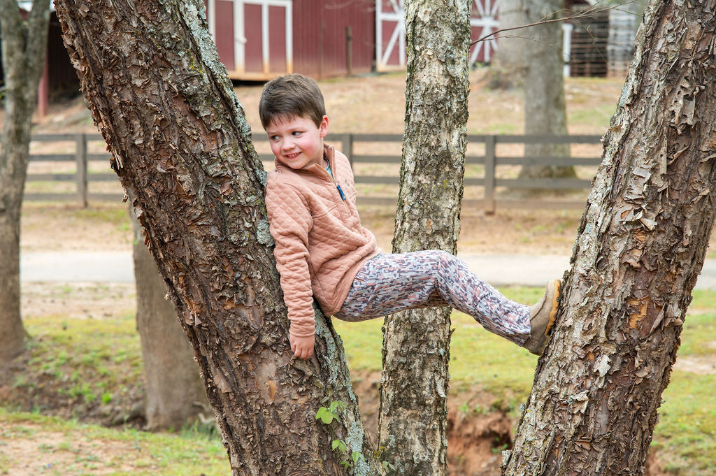 young boy sitting in a tree with new fall camo wear pants and top