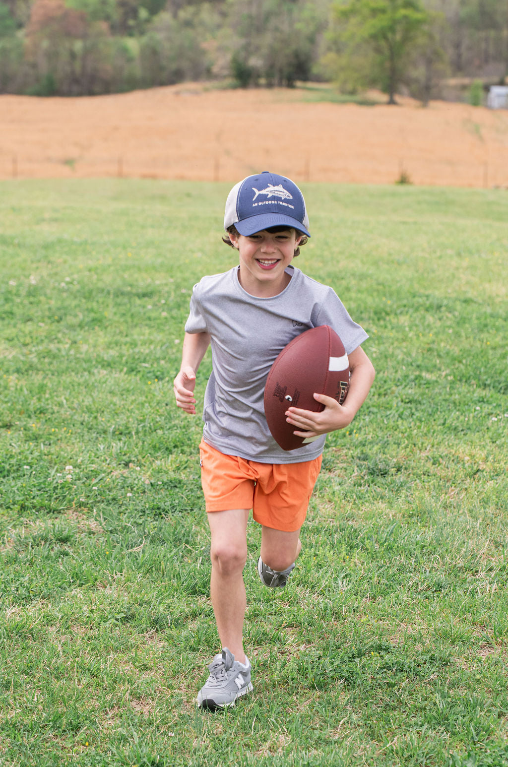 boy playing football with kids trucker hats with fish outline graphic