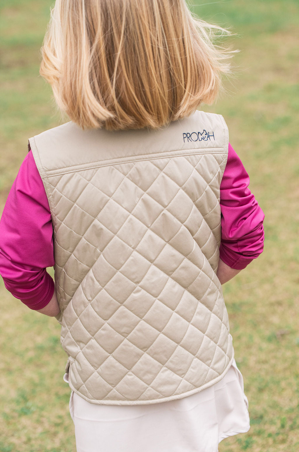 back view of young girl wearing a quilted khaki vests