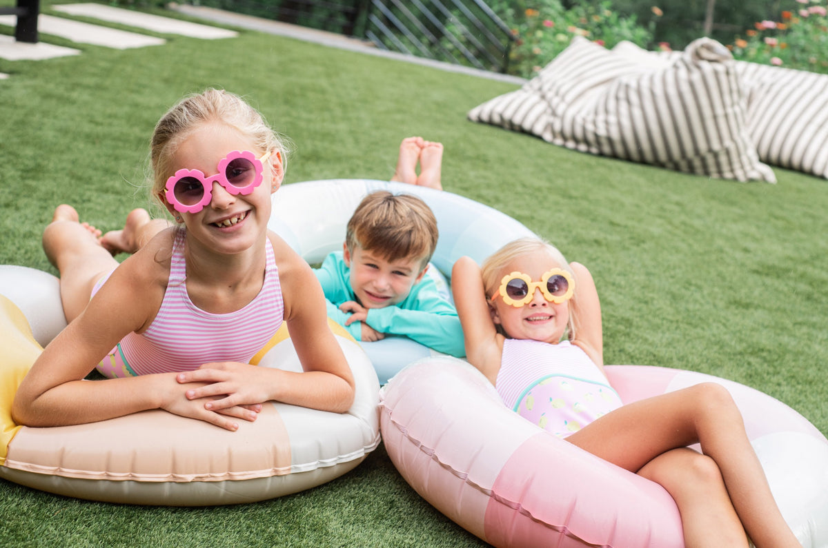 Children wearing one-piece swimsuits lying on inflatable pool toys