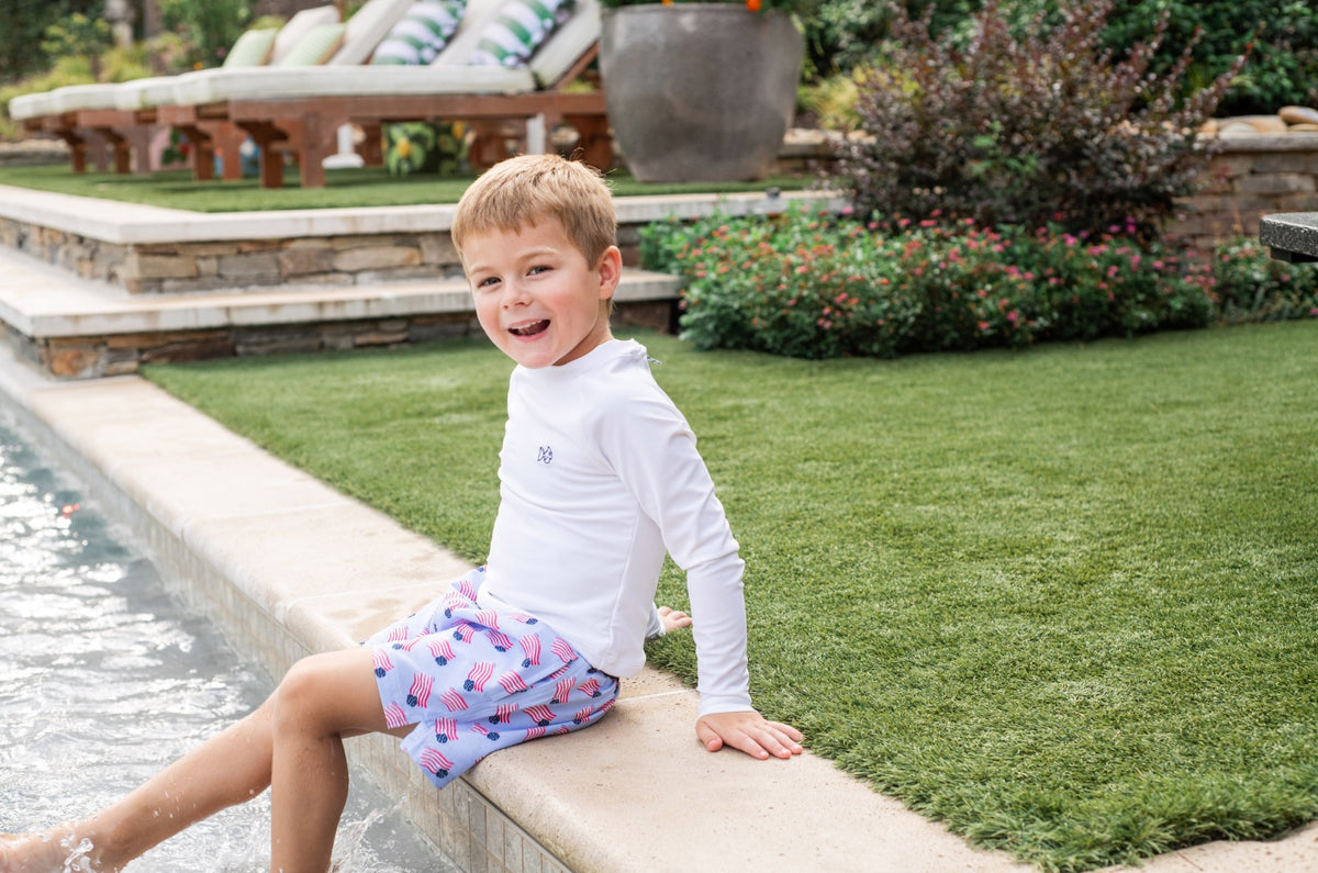 Child sitting by a pool with UPF 50+ Quick-Dry Anti-Chafe swim trunks