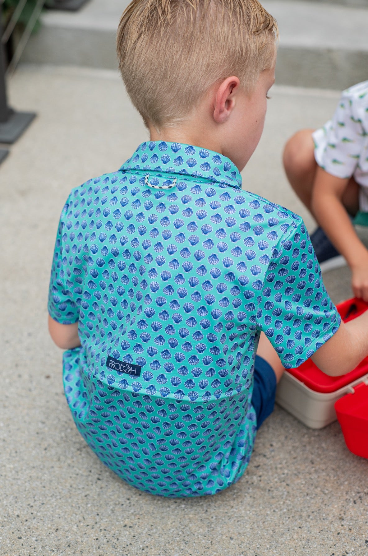 Child wearing a blue patterned seashell polo short sleeve shirt 