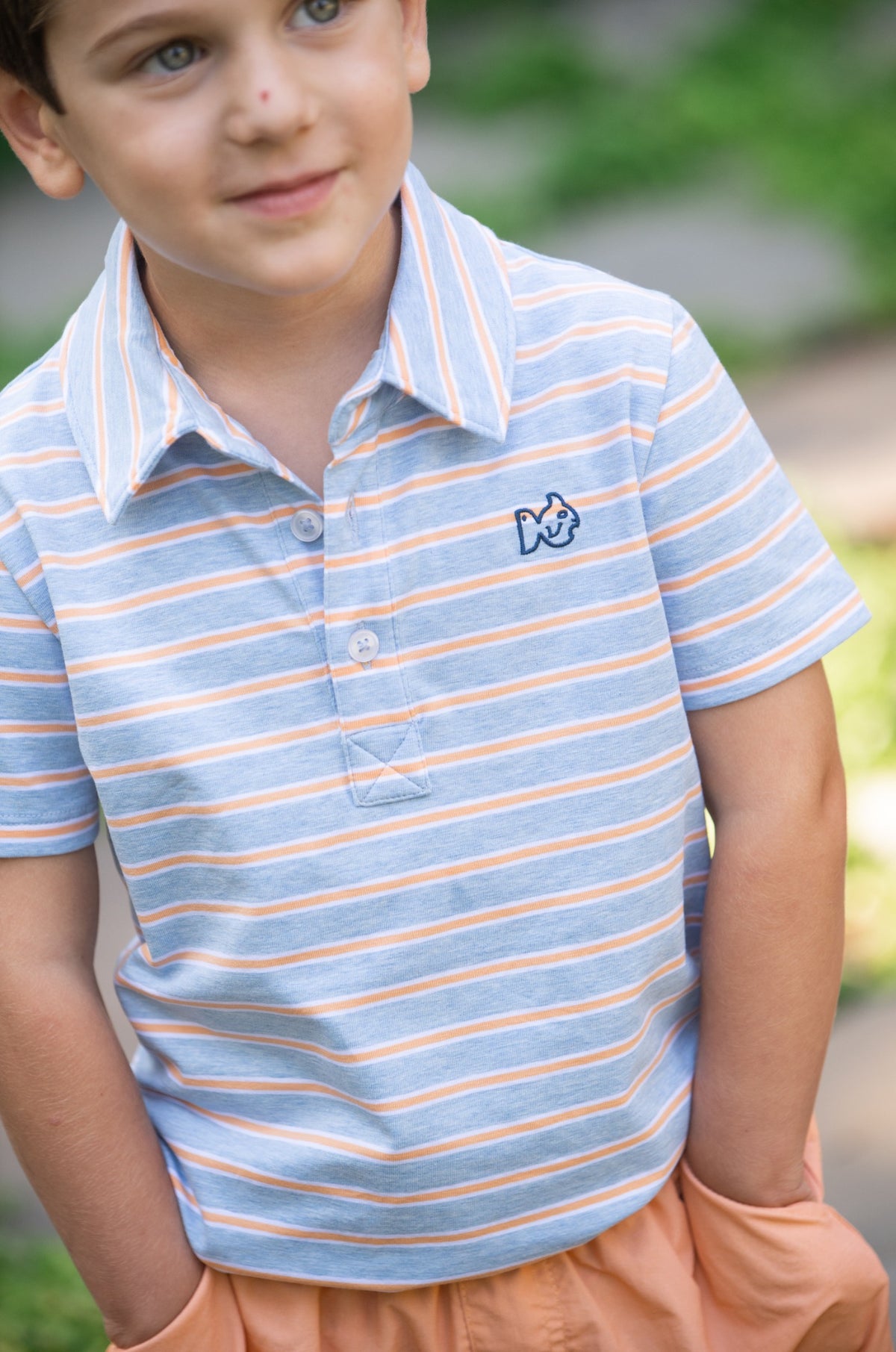 Young boy wearing a blue and orange striped cotton polo shirt 
