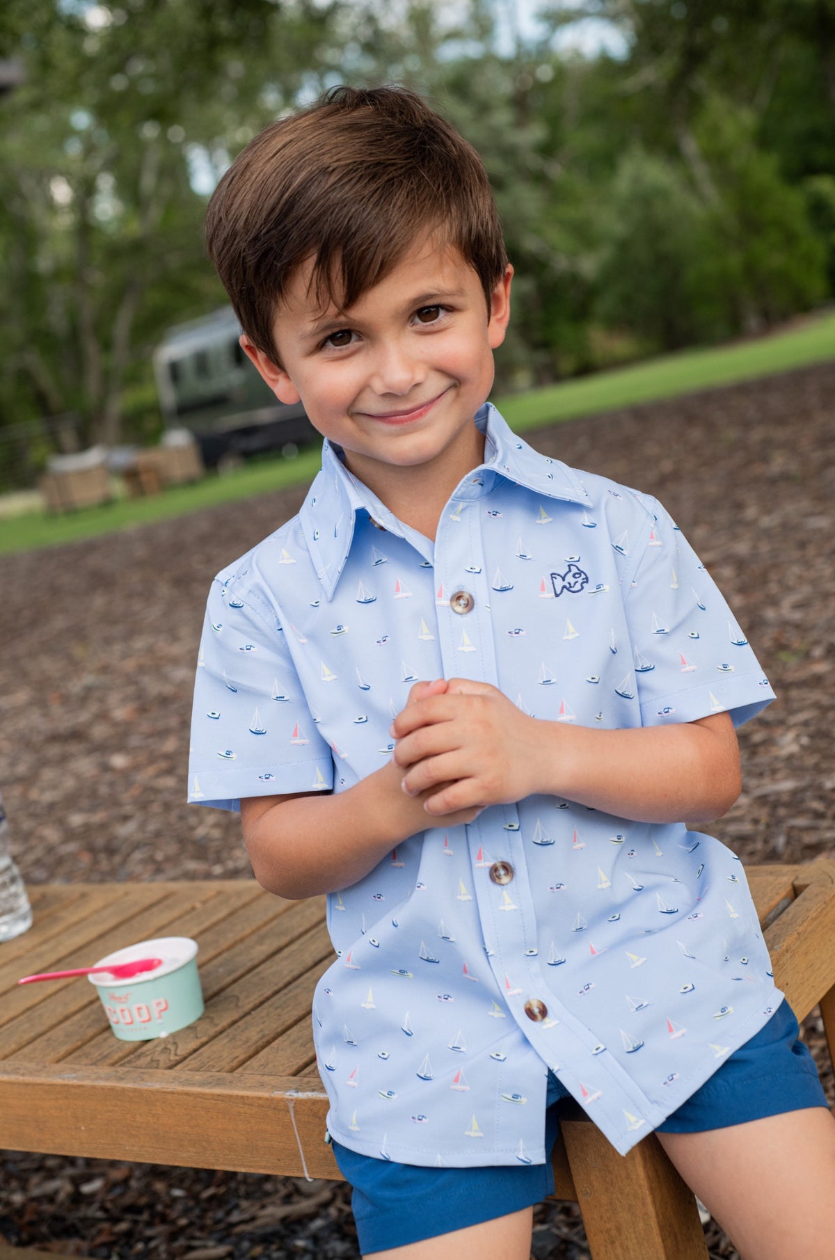 Young boy wearing a light blue shirt with buttons and boat pattern