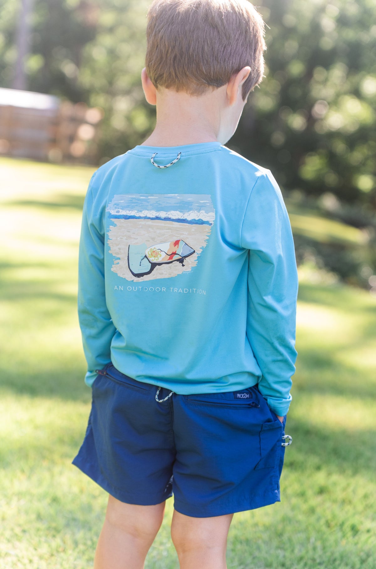 Child wearing a blue long-sleeve shirt with a graphic design outdoors