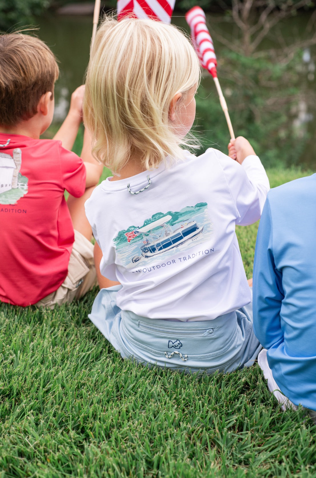 Children wearing a white long sleeve performance shirt with a boat design.