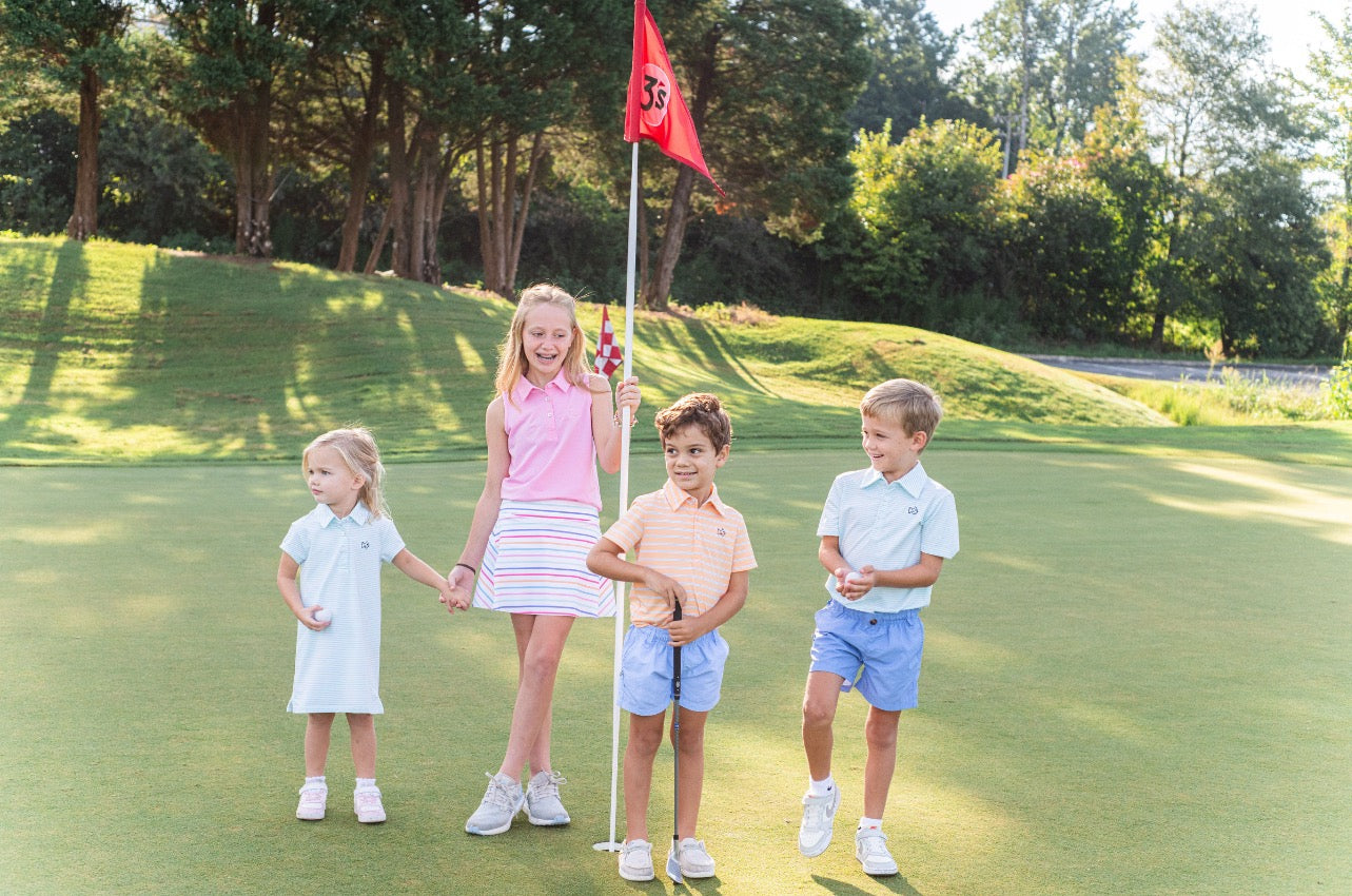 young girl on golf course wearing pink sleeveless polo