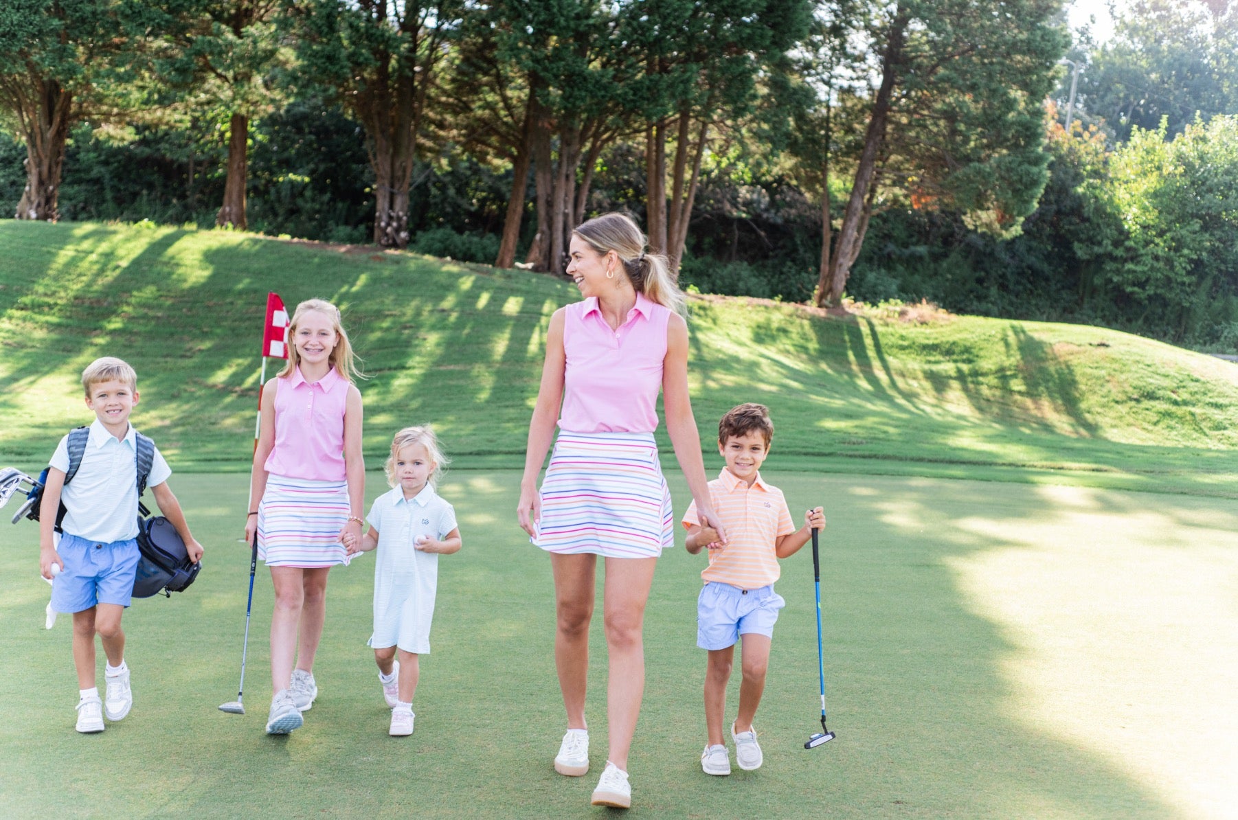 Woman with children on a golf course wearing pink sleeveless polo