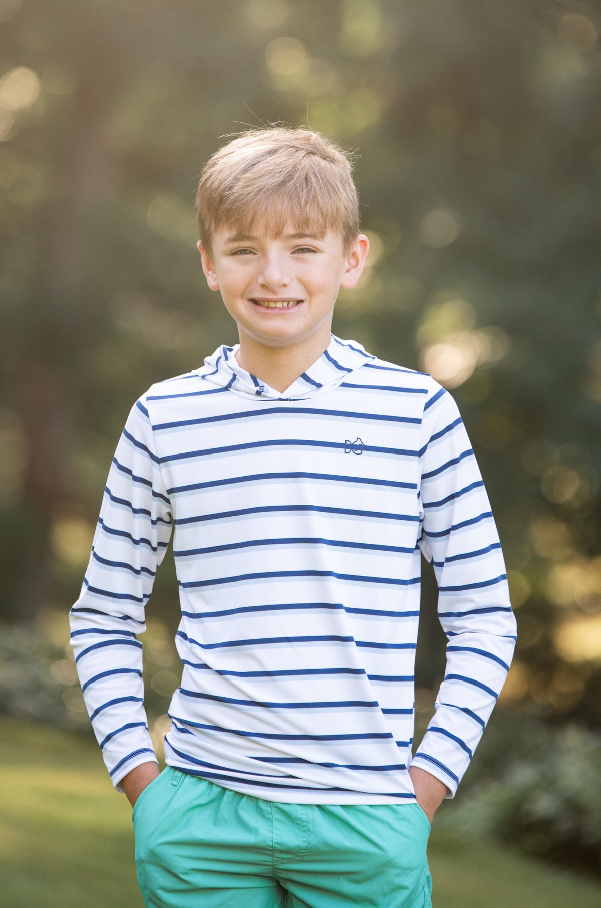 Young boy wearing a striped hoodie performance shirt and green shorts