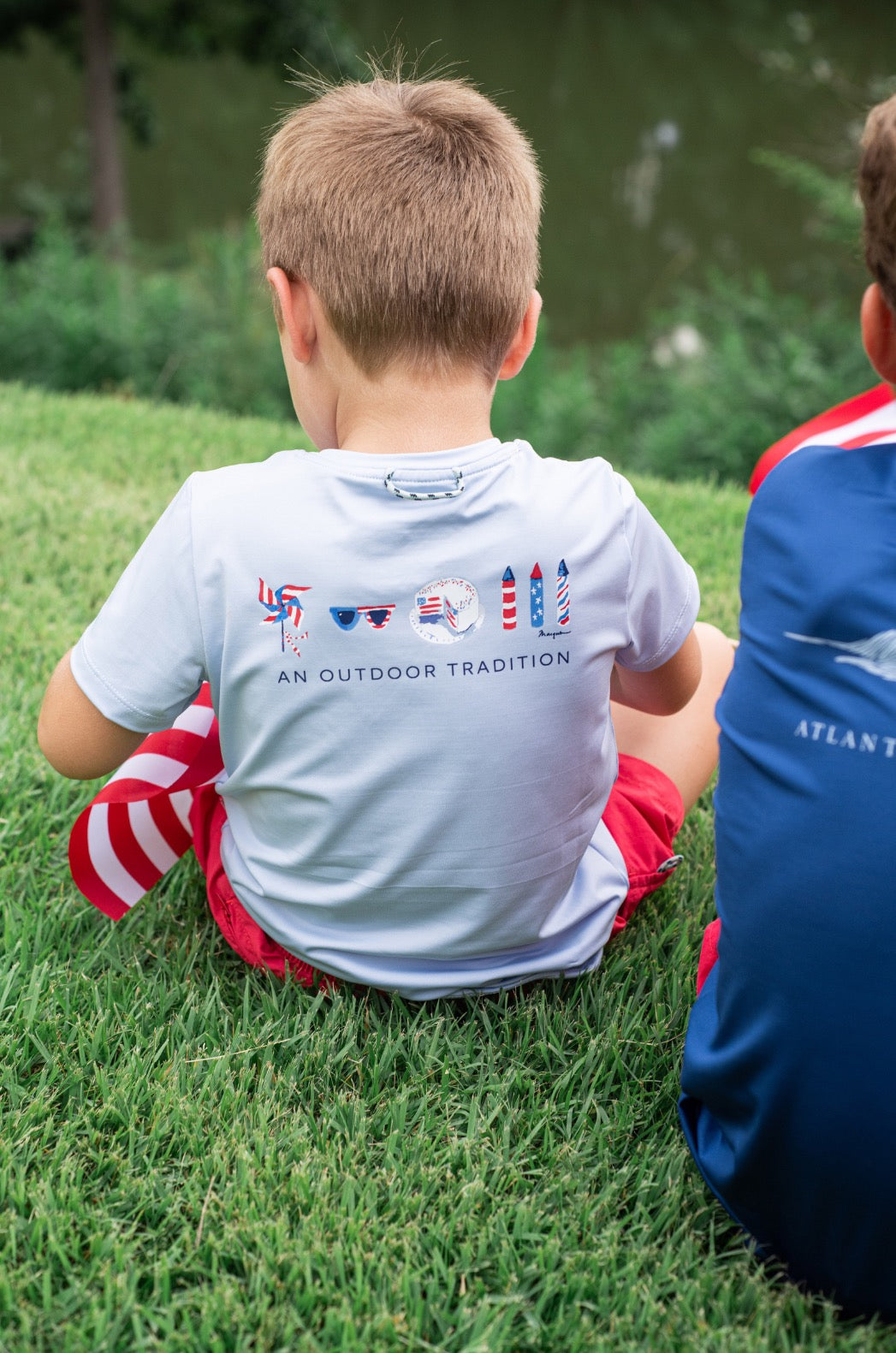 Two young children sitting on grass wearing activewear shirts
