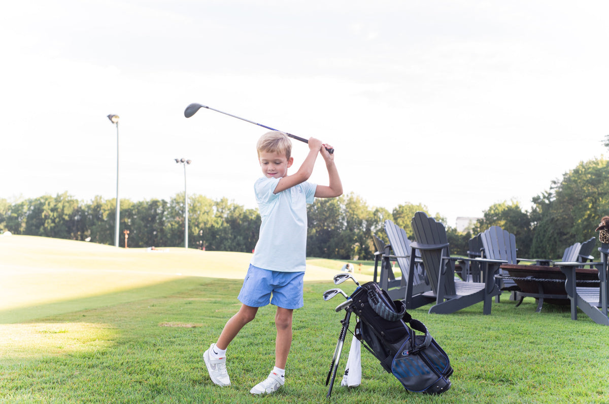Child playing golf on a grassy area wearing Performance Shorts in Ashleigh Blue