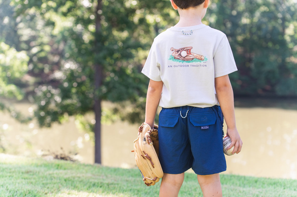 young boy wearing Performance navy Short and playing baseball in the yard