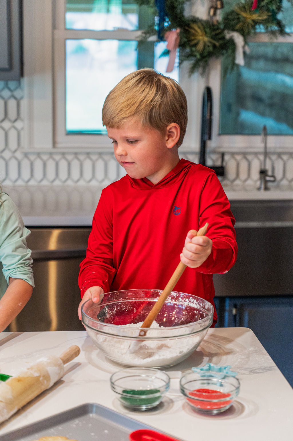 young boy  in a red shirt mixing ingredients in a bowl during christmas holiday